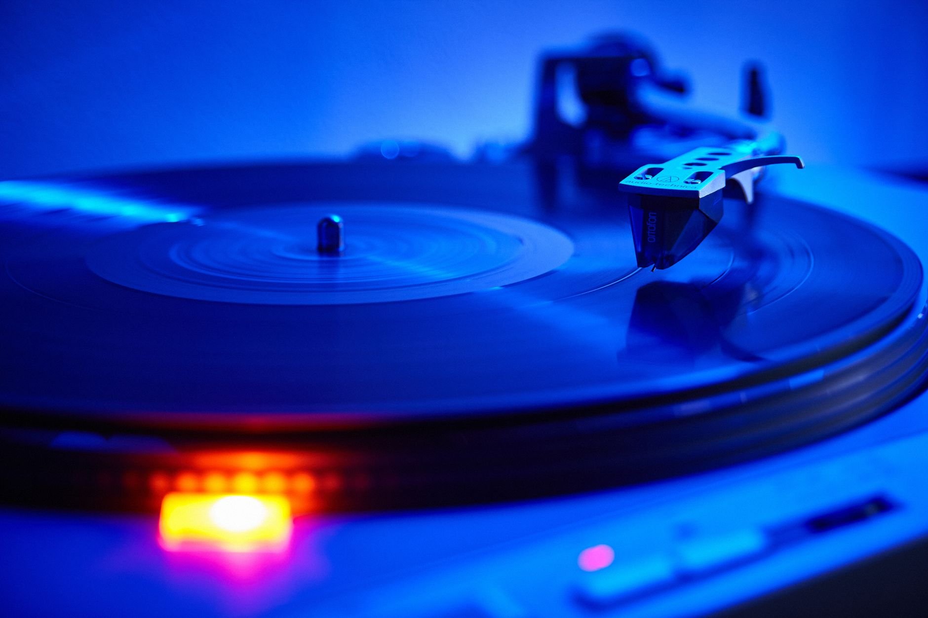Vinyl record spinning on a turntable, warm amber light.